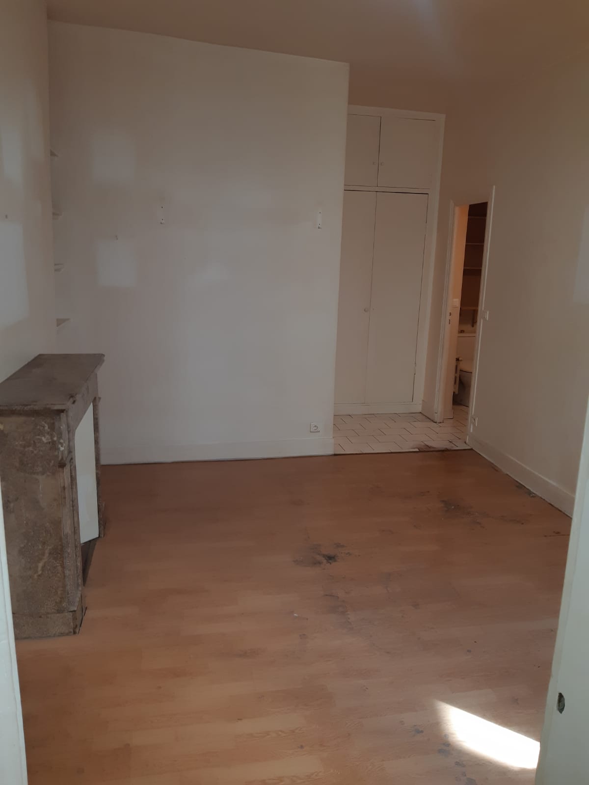 La même pièce entièrement vidée après le débarras, parquet et cheminée dégagés